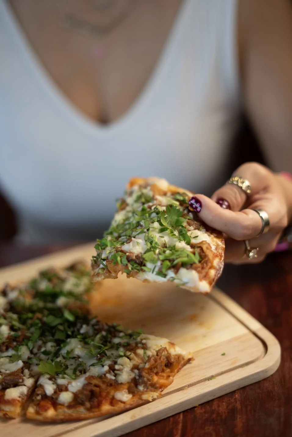 Una mano levanta una rebanada de pizzabirria.