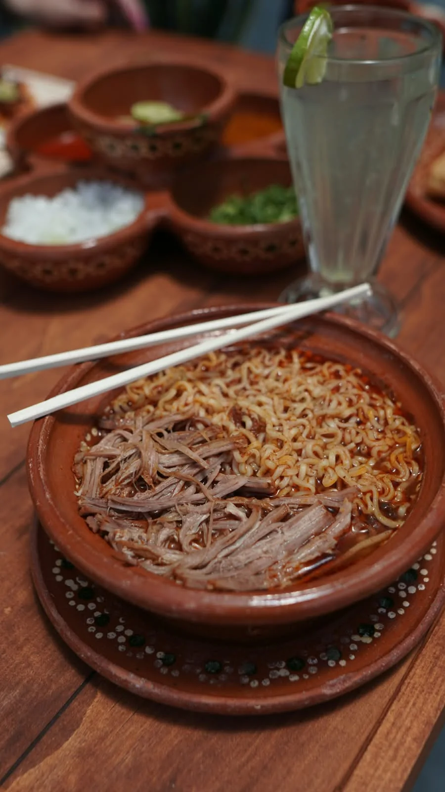 Birriamen en cazuela de barro, con palillos y agua fresca.