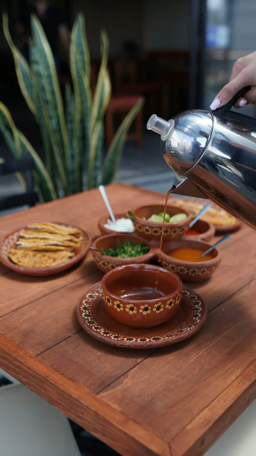 La mesa servida con tacos, salsas y consomé.