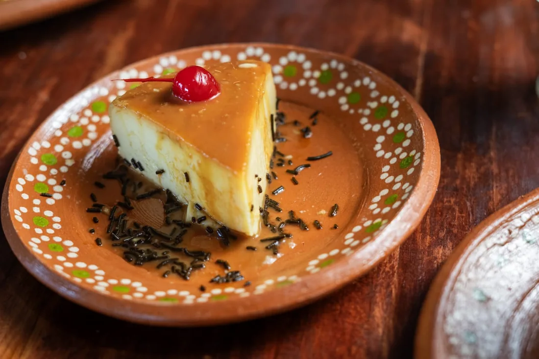 Rebanada de flan de cajeta en plato de barro.