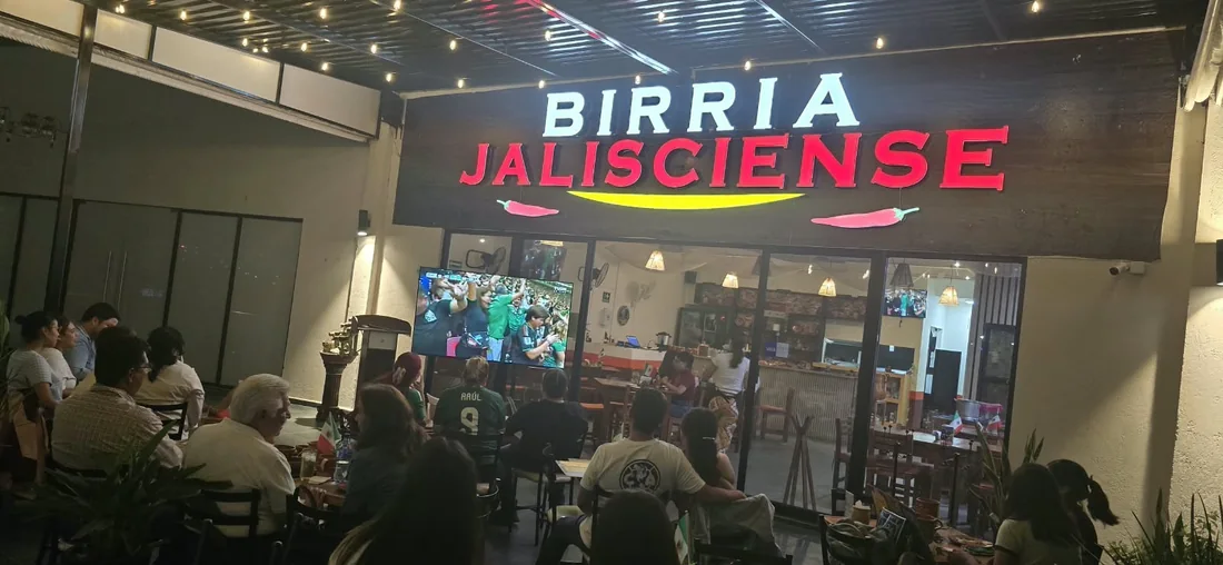 El local de noche, con el letrero encendido.