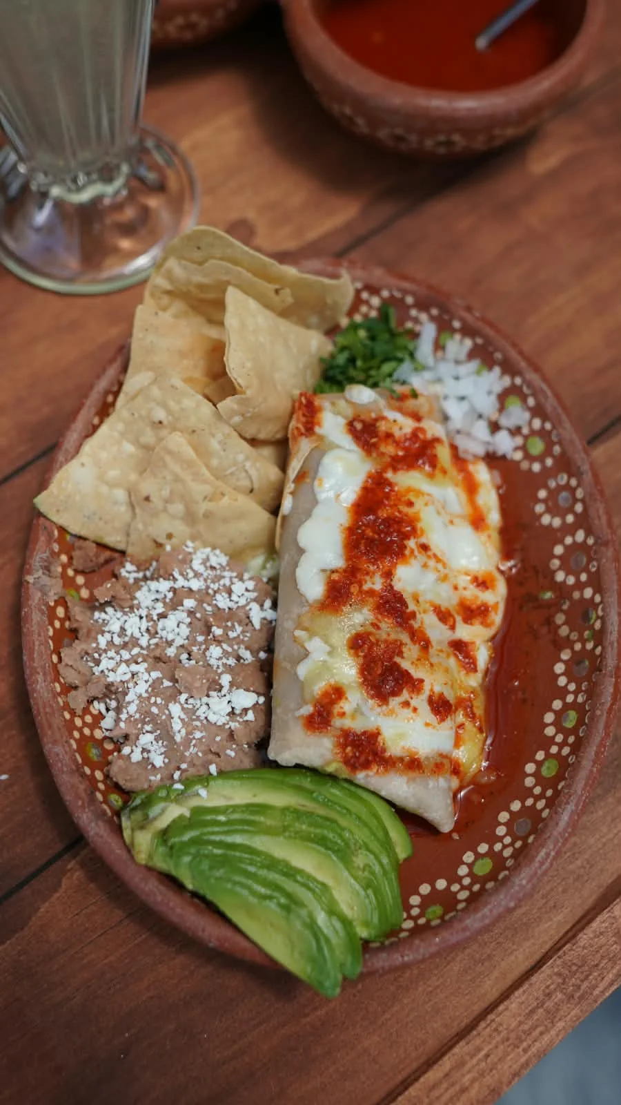 Burrito gratinado con frijoles refritos, totopos y aguacate.